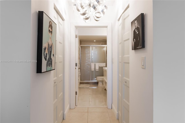 hallway with a notable chandelier and light tile patterned flooring