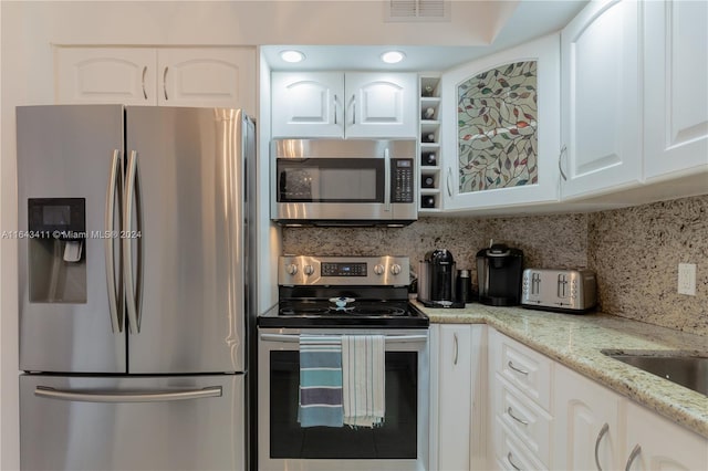 kitchen featuring white cabinetry, backsplash, stainless steel appliances, and light stone counters