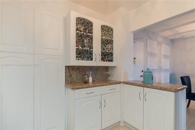 kitchen featuring stone counters, kitchen peninsula, and light tile patterned floors