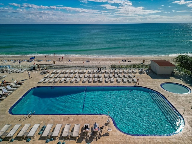 view of swimming pool with a patio area, a view of the beach, and a water view