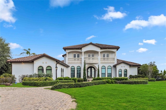 mediterranean / spanish house featuring a front lawn and a balcony