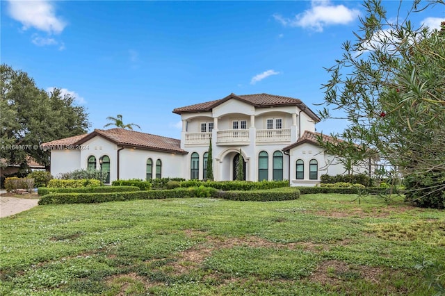 mediterranean / spanish home with a balcony and a front lawn