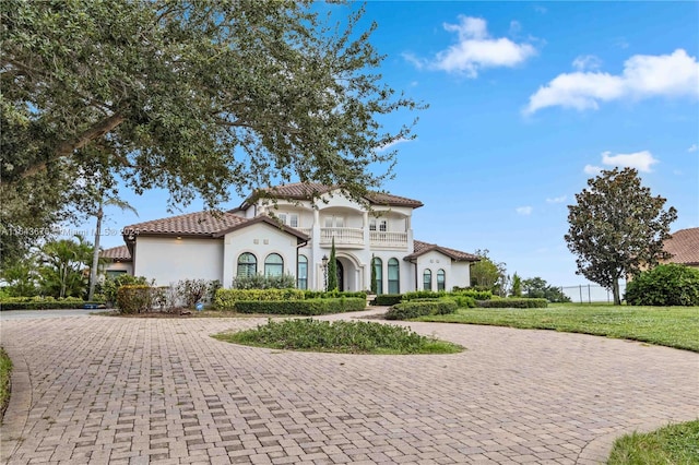 mediterranean / spanish-style home featuring a balcony and a front lawn