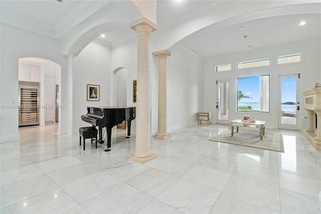 interior space featuring crown molding, wine cooler, and decorative columns