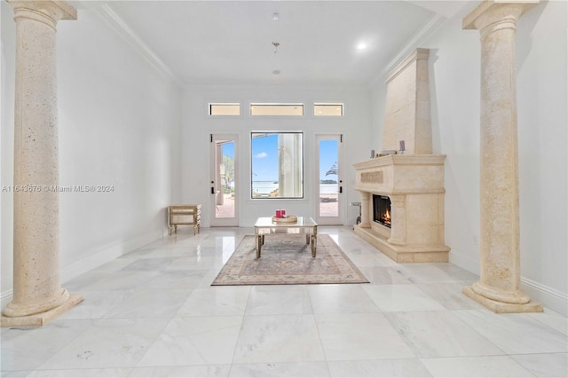 living room with crown molding, a large fireplace, and decorative columns