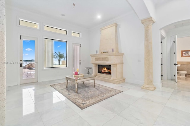 living area featuring a large fireplace, decorative columns, and ornamental molding