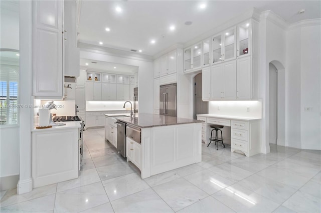 kitchen with crown molding, stainless steel appliances, white cabinetry, sink, and a kitchen island with sink