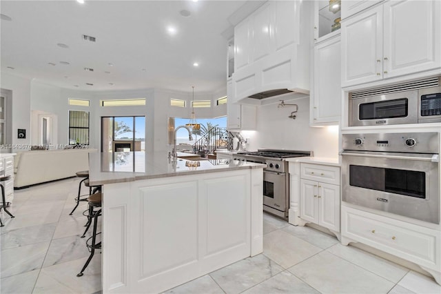 kitchen featuring a center island with sink, appliances with stainless steel finishes, a breakfast bar, sink, and white cabinets