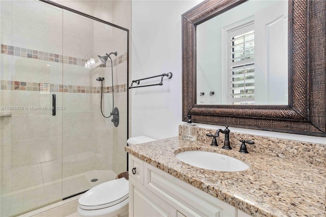 bathroom featuring toilet, a shower with door, and vanity