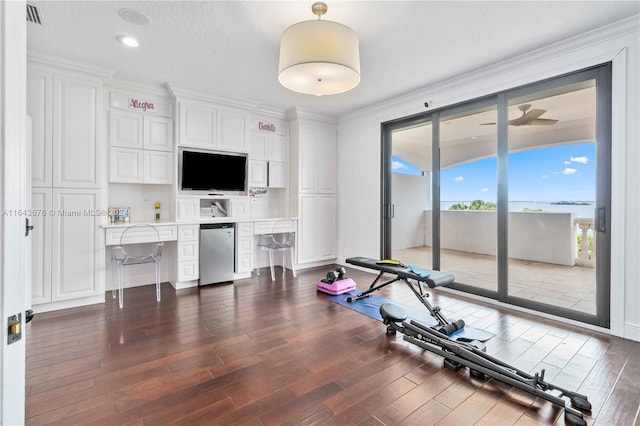 exercise area with built in desk, dark hardwood / wood-style flooring, and crown molding