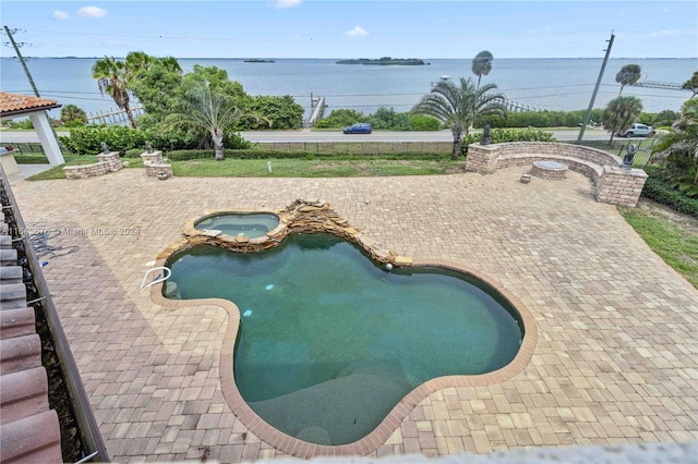 view of pool with an in ground hot tub, a patio, and a water view