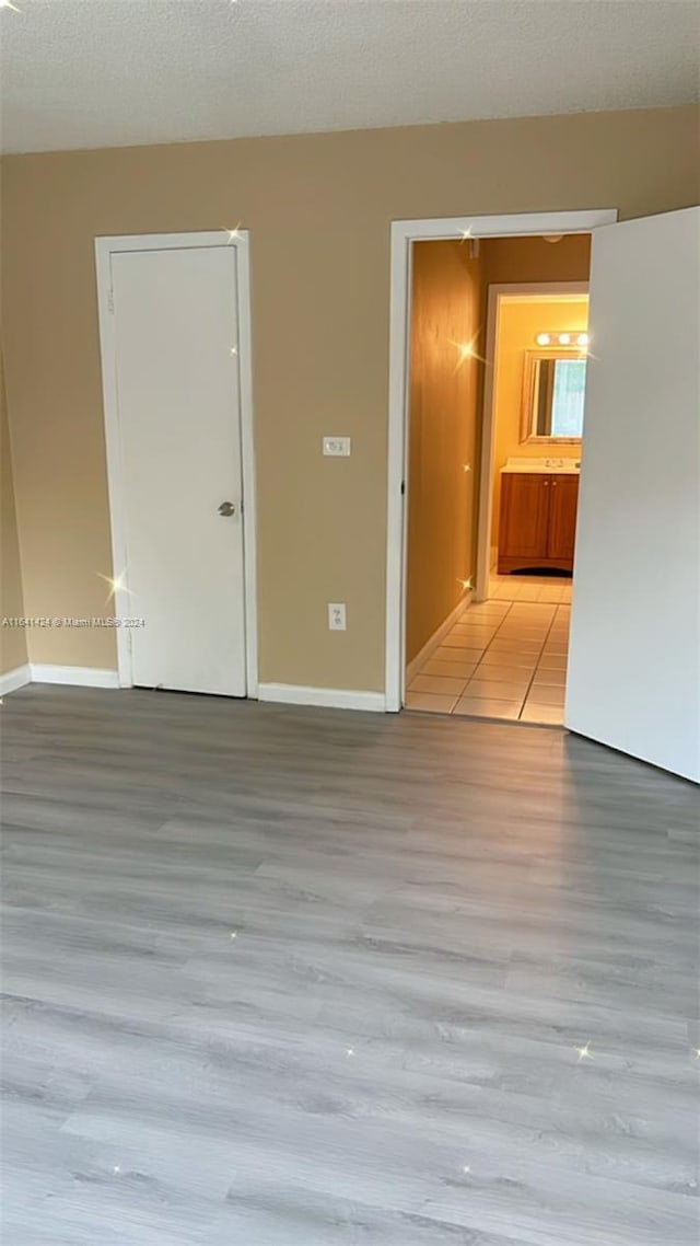 unfurnished room featuring light wood-type flooring and a textured ceiling