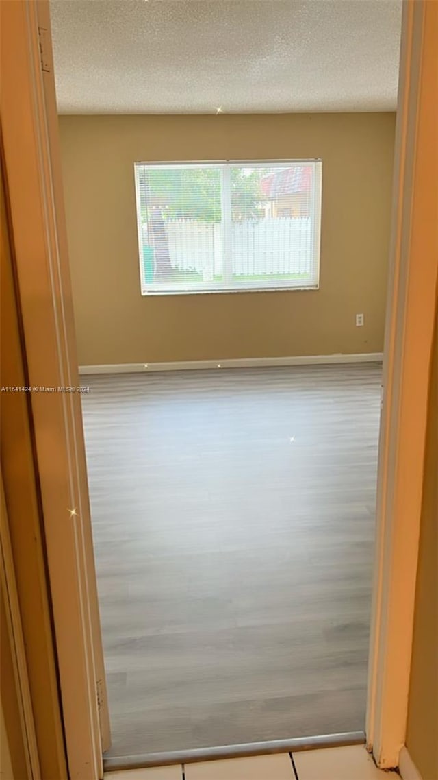 spare room featuring a textured ceiling and light hardwood / wood-style flooring