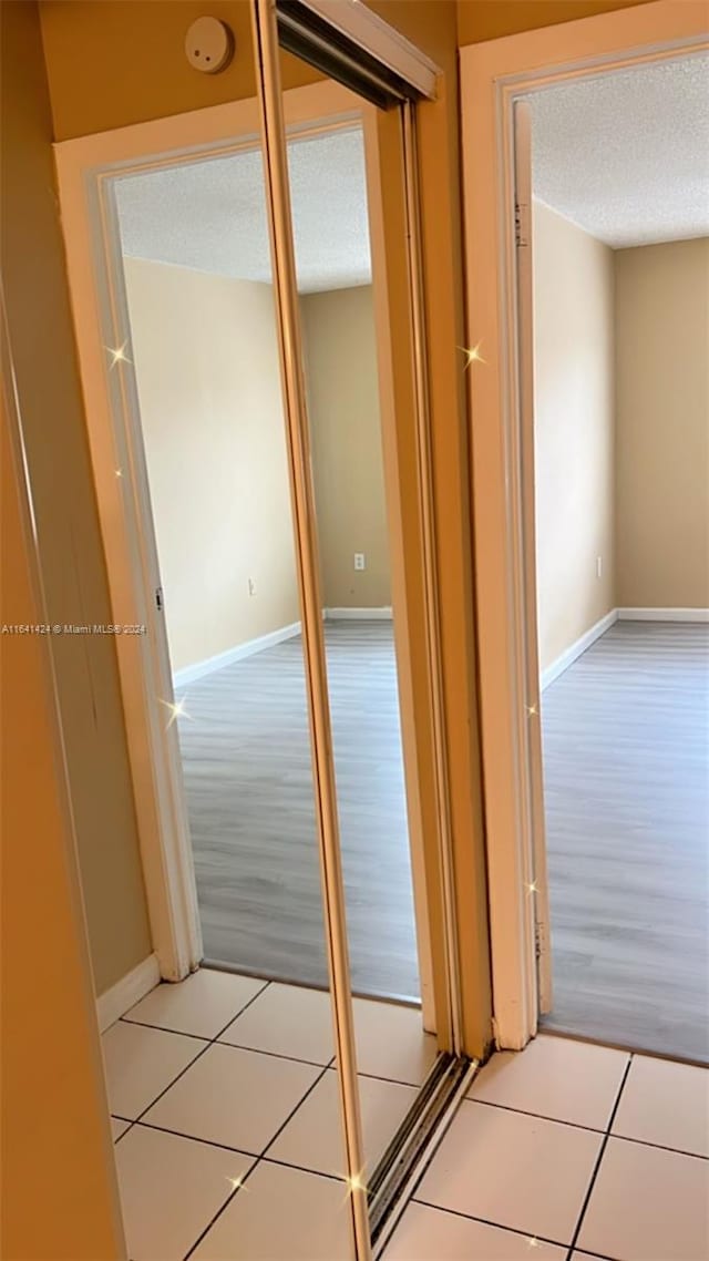 corridor with light tile patterned floors and a textured ceiling