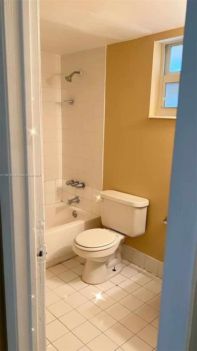 bathroom featuring tile patterned flooring, tiled shower / bath, and toilet