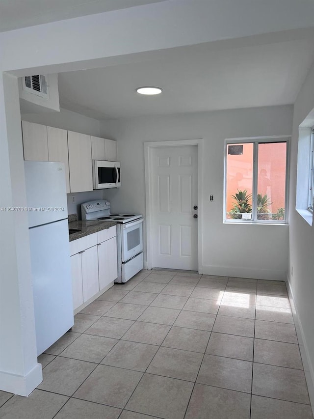 kitchen featuring light tile patterned flooring, white appliances, and white cabinets