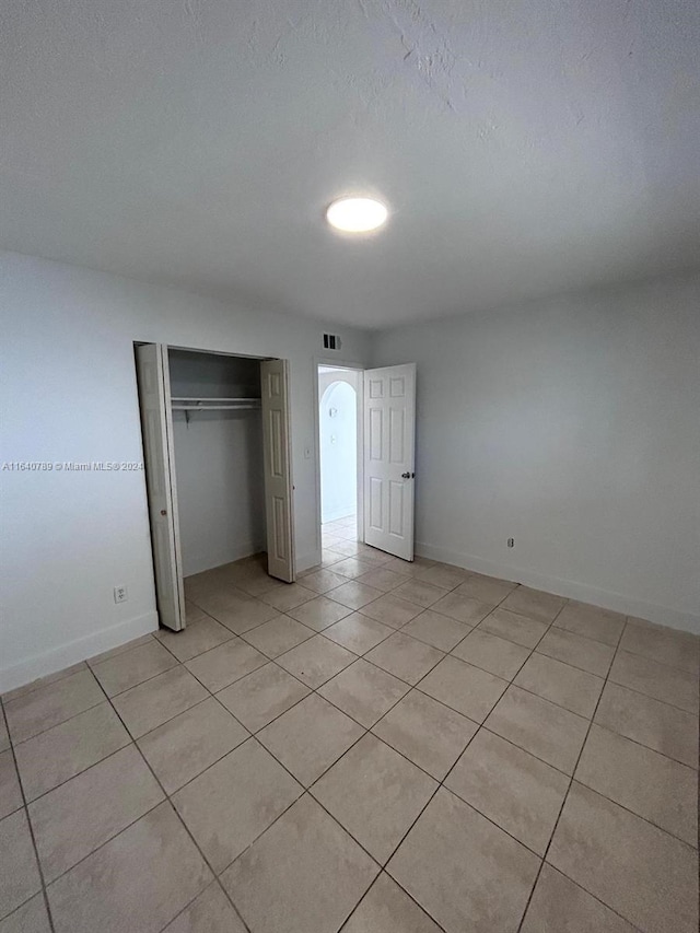 unfurnished bedroom featuring light tile patterned floors, a closet, and a textured ceiling