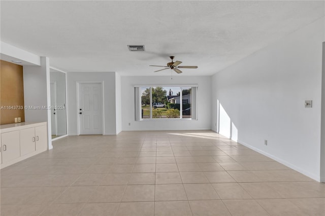 unfurnished living room with ceiling fan, light tile patterned floors, and a textured ceiling