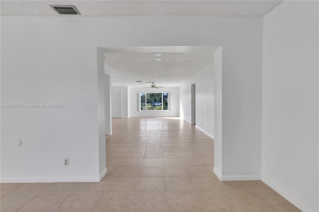 corridor with a textured ceiling and light tile patterned floors