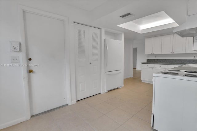 kitchen featuring light tile patterned floors, premium range hood, white appliances, and white cabinetry