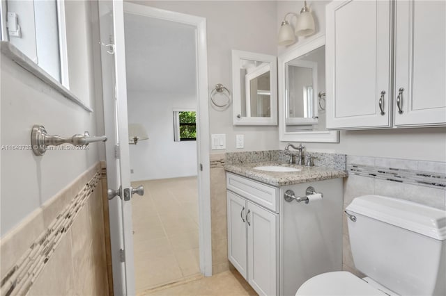 bathroom with toilet, vanity, and tile patterned floors