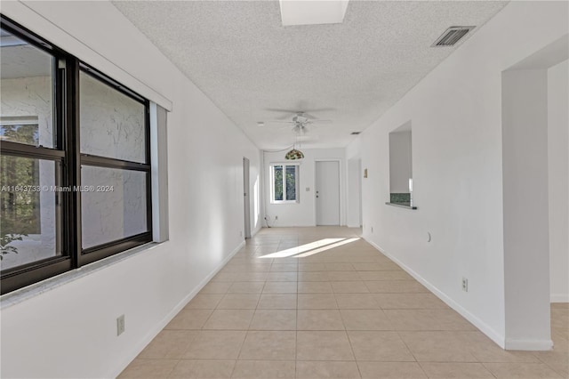 tiled spare room with a textured ceiling and ceiling fan