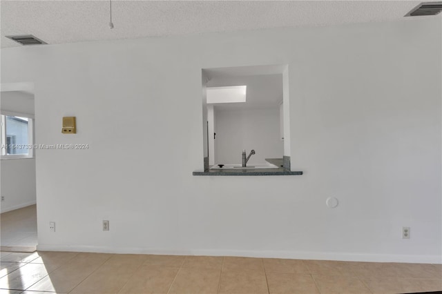 spare room with a textured ceiling, light tile patterned floors, and sink