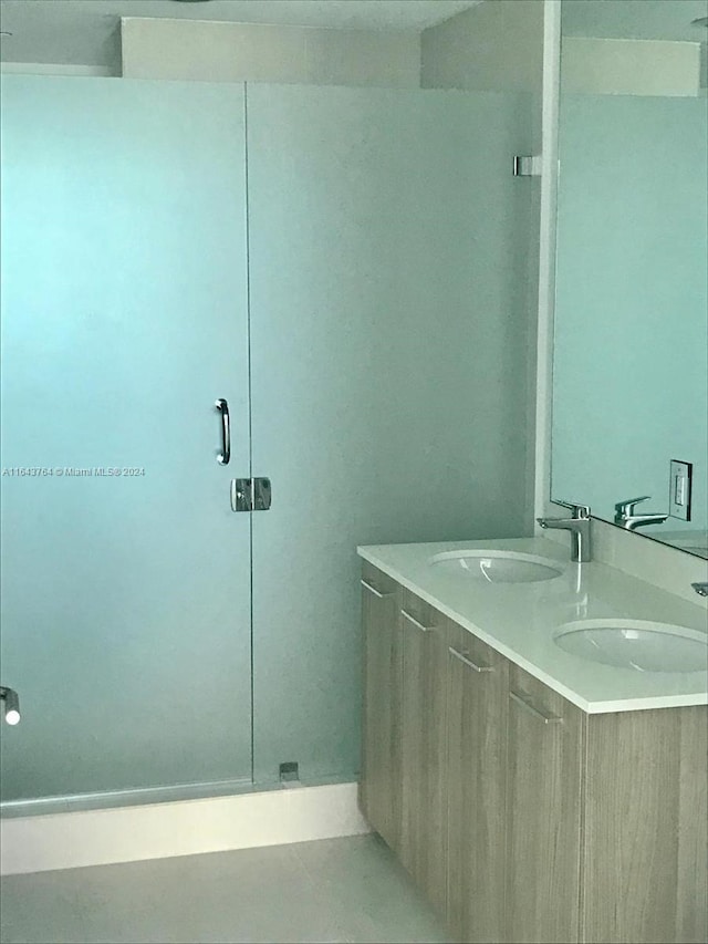 bathroom featuring double vanity and a shower with door