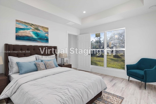 bedroom with wood-type flooring and a raised ceiling