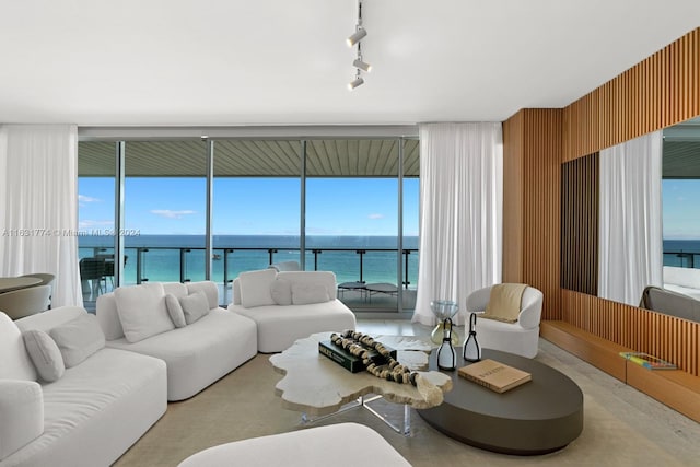 living room with a wall of windows, rail lighting, and a water view