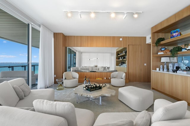 living room with wooden walls, a water view, and track lighting