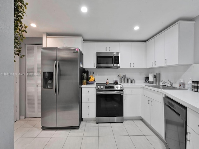 kitchen featuring sink, white cabinetry, light tile patterned floors, and stainless steel appliances