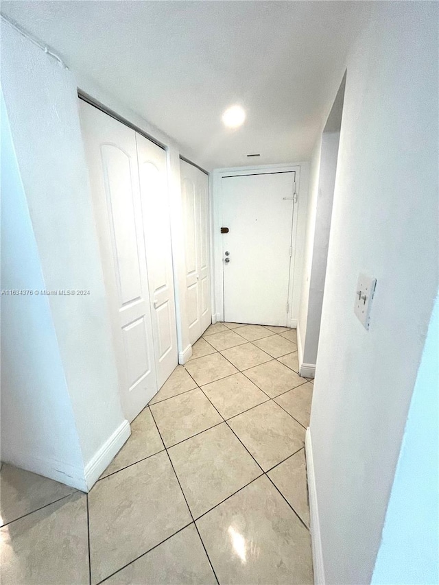 corridor with a textured ceiling and light tile patterned flooring