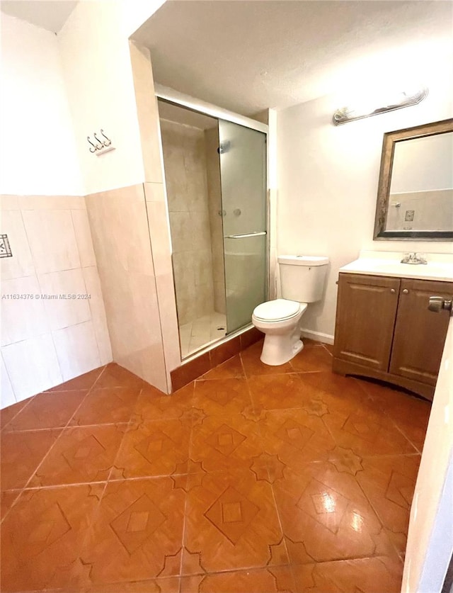 bathroom featuring tile patterned floors, a shower with door, vanity, and toilet