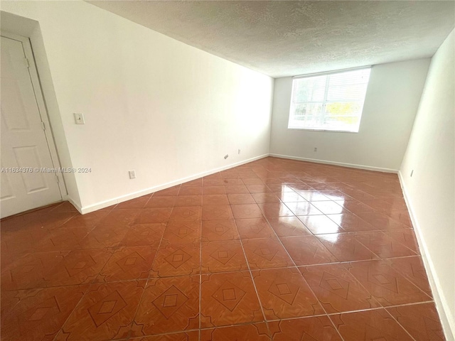 unfurnished room with tile patterned flooring and a textured ceiling