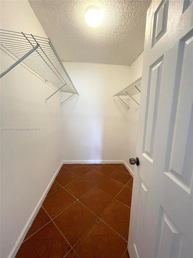 walk in closet with dark tile patterned flooring