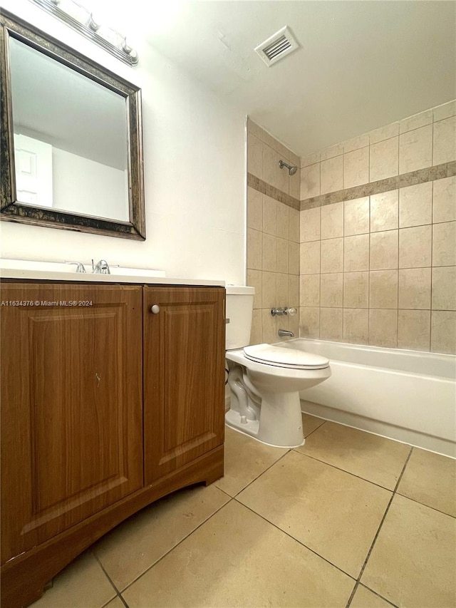 full bathroom with tile patterned flooring, vanity, tiled shower / bath combo, and toilet