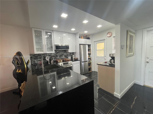 kitchen with white cabinetry, sink, dark stone countertops, dark tile patterned floors, and stainless steel appliances