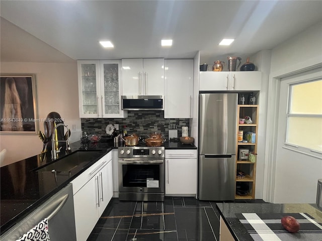 kitchen featuring appliances with stainless steel finishes, backsplash, dark tile patterned floors, sink, and white cabinets