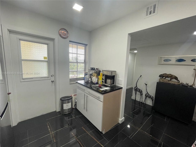 kitchen featuring white cabinets and dark tile patterned floors