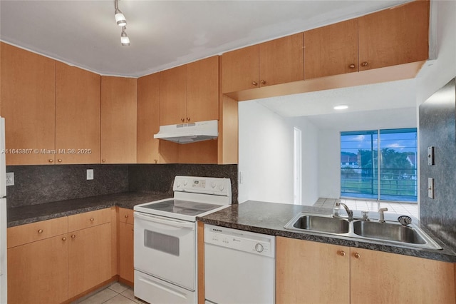 kitchen featuring tasteful backsplash, rail lighting, sink, light tile patterned floors, and white appliances