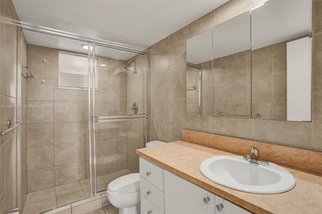 bathroom with tile walls, vanity, walk in shower, toilet, and tile patterned floors