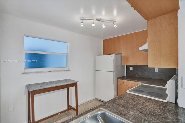 kitchen featuring light tile patterned floors, white refrigerator, backsplash, range hood, and stove