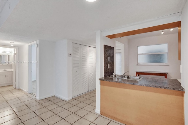 kitchen featuring sink, a textured ceiling, and light tile patterned floors