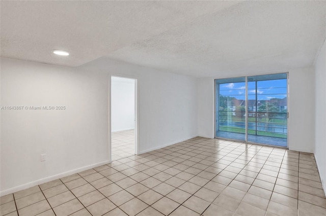 tiled empty room featuring a wall of windows and a textured ceiling