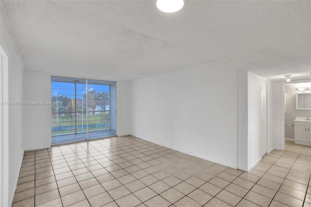 tiled empty room with expansive windows and a textured ceiling