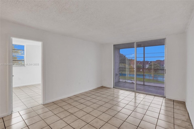 unfurnished room with light tile patterned flooring, floor to ceiling windows, and a textured ceiling