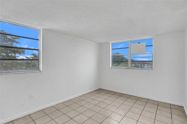 spare room with a textured ceiling and light tile patterned floors