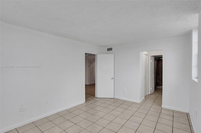 tiled spare room featuring a textured ceiling