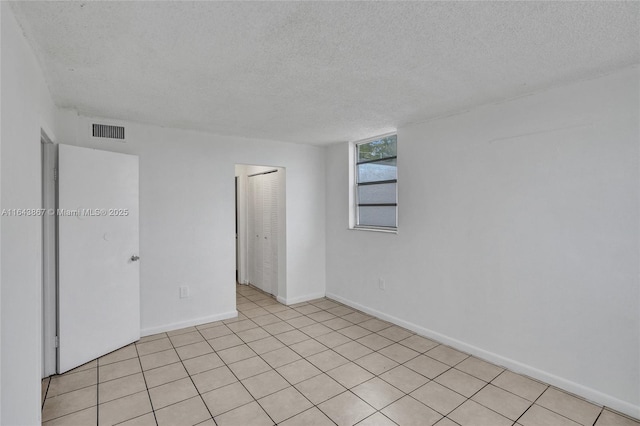 tiled empty room featuring a textured ceiling